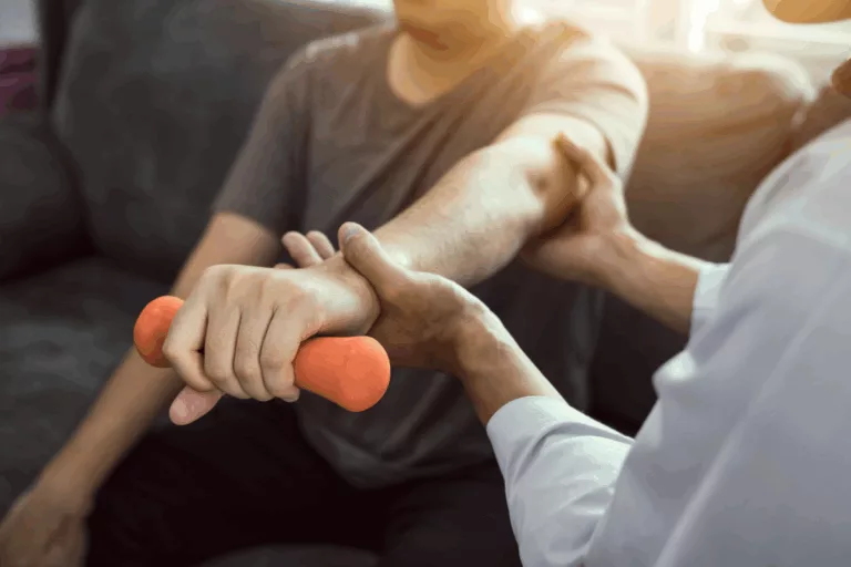 Kinésithérapeutes aidant un patient à effectuer un exercice de rééducation du bras avec un haltère orange.